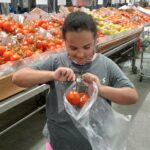 Student picking tomatoes at Farmer's Market community trip