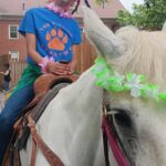 Student posing on horse at the Last Day Luau